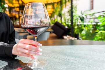 Close-up of a hand holding a glass of red wine in a well-lit restaurant