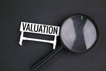 magnifying glass and a white sign with the word valuation. the concept of something that has value