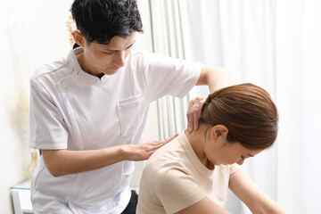 Fototapeta premium 女性患者にマッサージ整体の施術をする男性