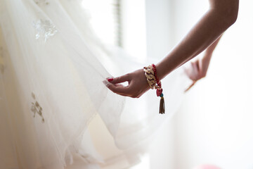 A bride or bridesmaid carefully adjusts the laces or buttons of a wedding dress, highlighting the...