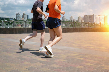 A middle-aged man and woman are running together along the river embankment.