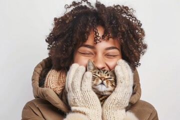 A woman is holding a cat in her arms while wearing a white scarf