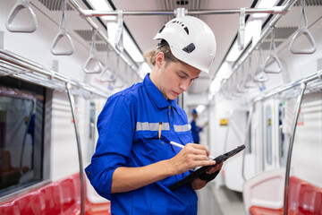 Portrait of young engineer of electric locomotive holding tablet in train
