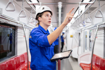 Portrait of young engineer of electric locomotive holding tablet in train