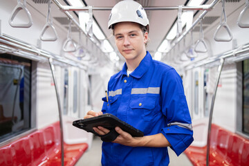 Portrait of young engineer of electric locomotive holding tablet in train