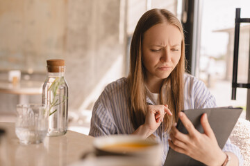 Portrait upset sad skeptical unhappy serious woman using mobile pad computer displeased with email...