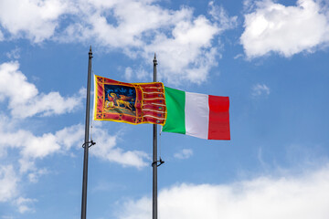 Flags of Italy and Veneto Region waving in the wind; blue sky with clouds