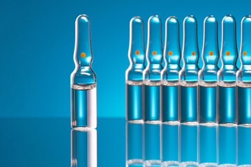 Vials of medicine. Medical glass ampoules with vaccine on a blue background. Selective focus  on a...