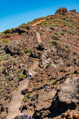 Female hiker climbing a steep path between volcanic rocks, Canary Islands, La Palma.