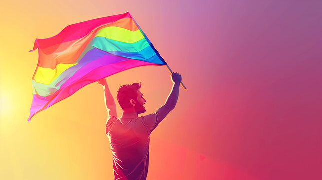 Young man is holding a rainbow flag and smiling while standing in front of a rainbox colored background , celebrating lgbtq plus pride and equality