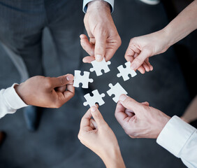 Hands, puzzle and above for teamwork in office with business people, support and connection for solution. Group, scrum and jigsaw with synergy, strategy and problem solving with link in workplace
