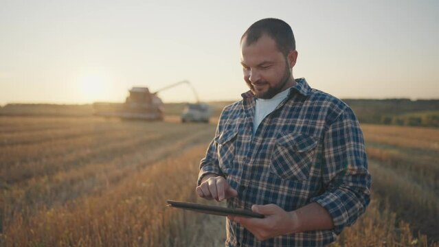 Portrait of agronomist with tablet on wheat field in harvest time, agribusiness. Professional and experienced farmer using mobile gadgets, growing cereals in ecological area, farming and agriculture