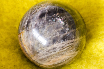 Gleaming moonstone sphere on vibrant yellow blanket