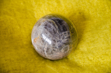 Polished moonstone sphere on bright yellow blanket