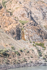 Rocky mountain range with vegetation in the mountains of Tajikistan in the Pamir in the valley of the Panj River, landscape for the background