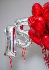 silver balloons number 15 on a background of red hearts
