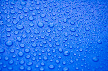Close up of water droplets on blue cover background.