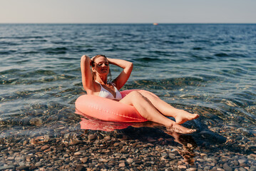 A woman is floating on a red inflatable tube in the ocean