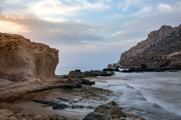 View of the fine sand and rock beaches at Playa Amarilla in Aguilas, Region of Murcia, Spain, with transparent waters and Isla del Fraile in the background taken with long exposure