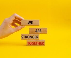 We are stronger together symbol. Wooden blocks with words We are stronger together. Businessman hand. Beautiful yellow background. We are stronger together concept. Copy space.