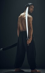 Martial arts, back and samurai or ninja in studio with sword, exercise and fitness for dojo. Blade, wellness and Asian man or warrior by black background for karate, sports and battle in training © Lumeez23/peopleimages.com