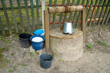 Metal and plastic water buckets on old draw well