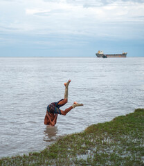 South asian young rural boy diving in the river water 