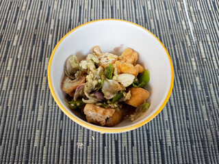 Delicious Tahu Gejrot Dish in a White Bowl on Blue Textured Background with Crispy Tofu and Spicy Sweet Sauce, Indonesian Cuisine Close up