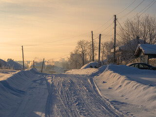 Snowy foggy road in countryside with snow drifts in frosty winter.