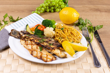 a dinner plate filled with a grilled deboned branzino fish filets and assorted vegetables in a...