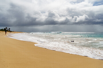 A beach on a cloudy day with waves crashing on the shore