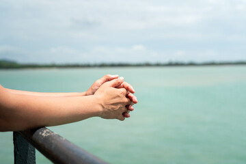 Close-up at people arm and hand part during leaning on handrail at the passenger deck to ferryboat with blue ocean background. Transportation for travel concept scene. 