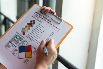 Action of a safety supervisor hand is checking on checklist of chemical and hazardous material form...