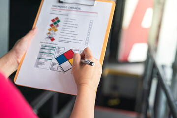 Action of a safety supervisor hand is checking on checklist of chemical and hazardous material form...