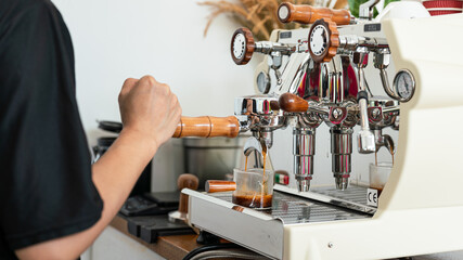 Action of a barista is making fresh coffee by using automatic coffee machine. Close-up and selective focus.