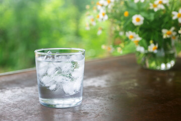 a glass of cold water with ice on rustic table.