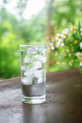 a glass of cold water with ice on rustic table.