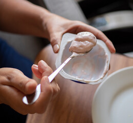 Concept of taking or grabbing food with hands, feminine Mexican hands. strawberry yogurt on a spoon feeding a child or a baby square image