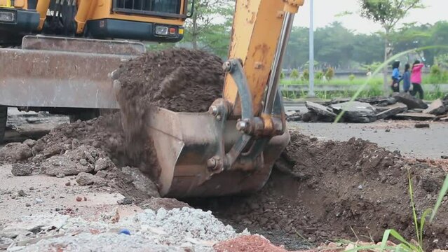 Excavator digs trench in the construction site, close up backhoe digger