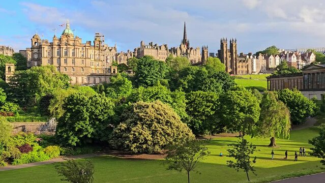 Slow panning motion over the old city of Edinburgh, Scotland from Princes Street Gardens near sunset