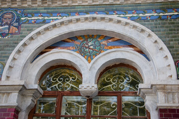 The entrance arch is decorated with a sun and a cross. the facade of a religious temple
