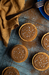mini salted caramel and chocolate tarts on a wire rack