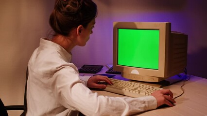 Young woman is typing on old vintage computer keyboard close-up. Work office place concept, old monitor with chroma key screen. Working and chatting in personal old pc computer with green screen.