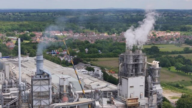 Aerial view of steam and smoke being emitted from industrial factory in countryside