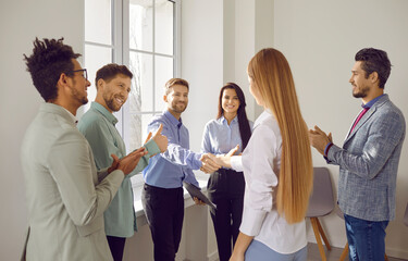 Team of business people showing recognition and appreciation to a young colleague. Smiling male...