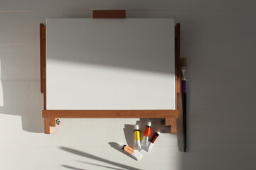 Empty copy space canwas on wood easel and paintbrush in artistic workshop interior