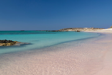 Sandy beach background. Gentle waves crash upon the shore. Pink sand. Pink shells. Elafonisi. Crete. Greece.