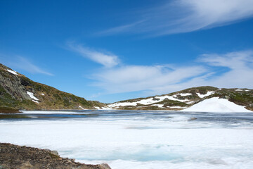 Frozen lake between mountains and blue sky
