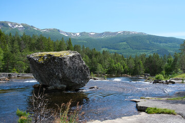 Big stone in a river with beautiful forest and mountains