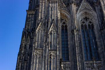 Gothic facade and windows of Hohe Domkirche St. Petrus (Cologne Cathedral) with blue sky in Cologne, Germany
